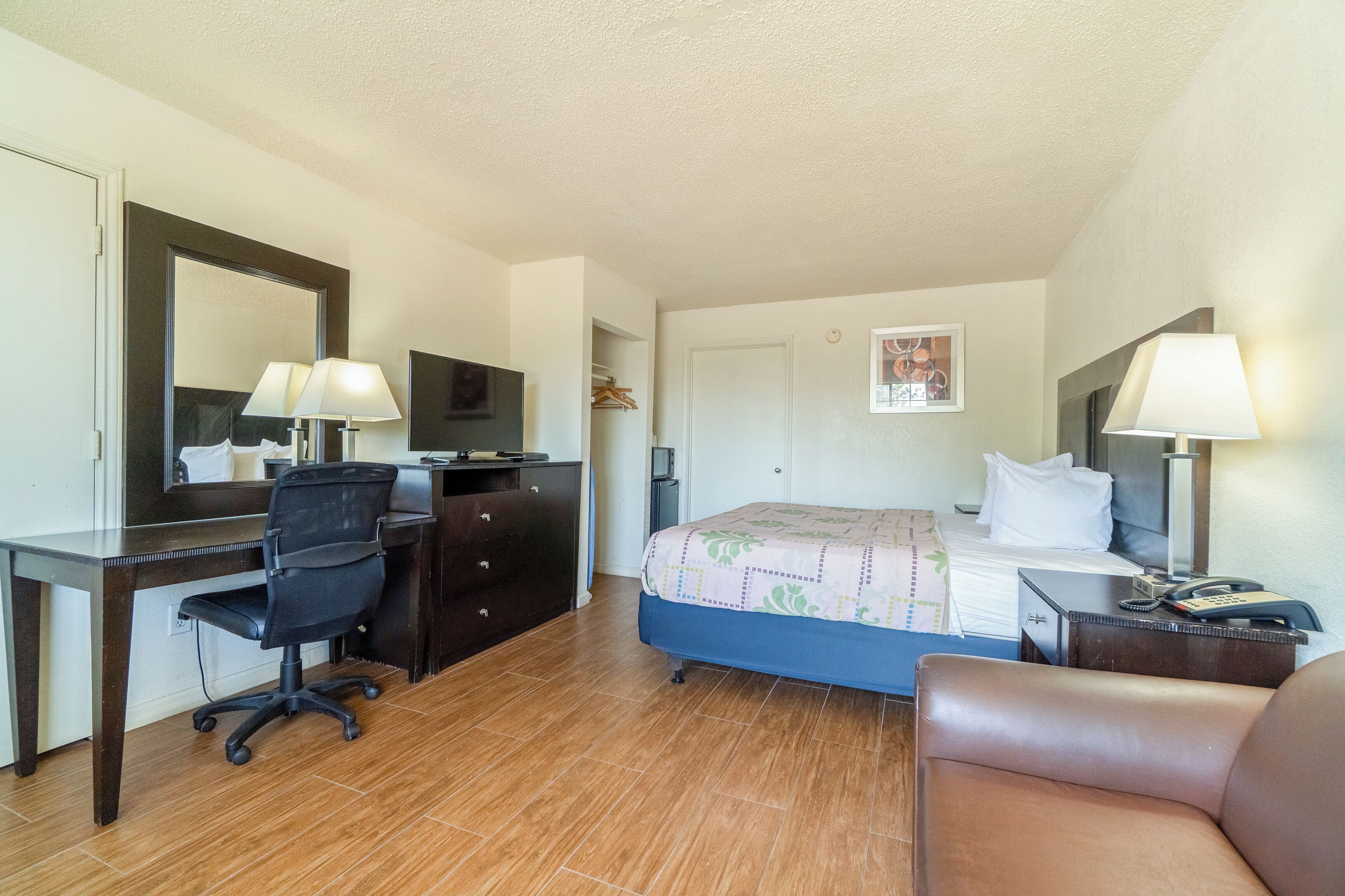 Een hotelkamer met een bed, bureau, stoel en een dressoir.