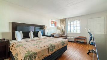 Habitación de hotel con una cama grande, un escritorio, una silla, una ventana con cortinas y una puerta.