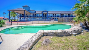 A hotel with a swimming pool, a covered outdoor area, and a view of the ocean.
