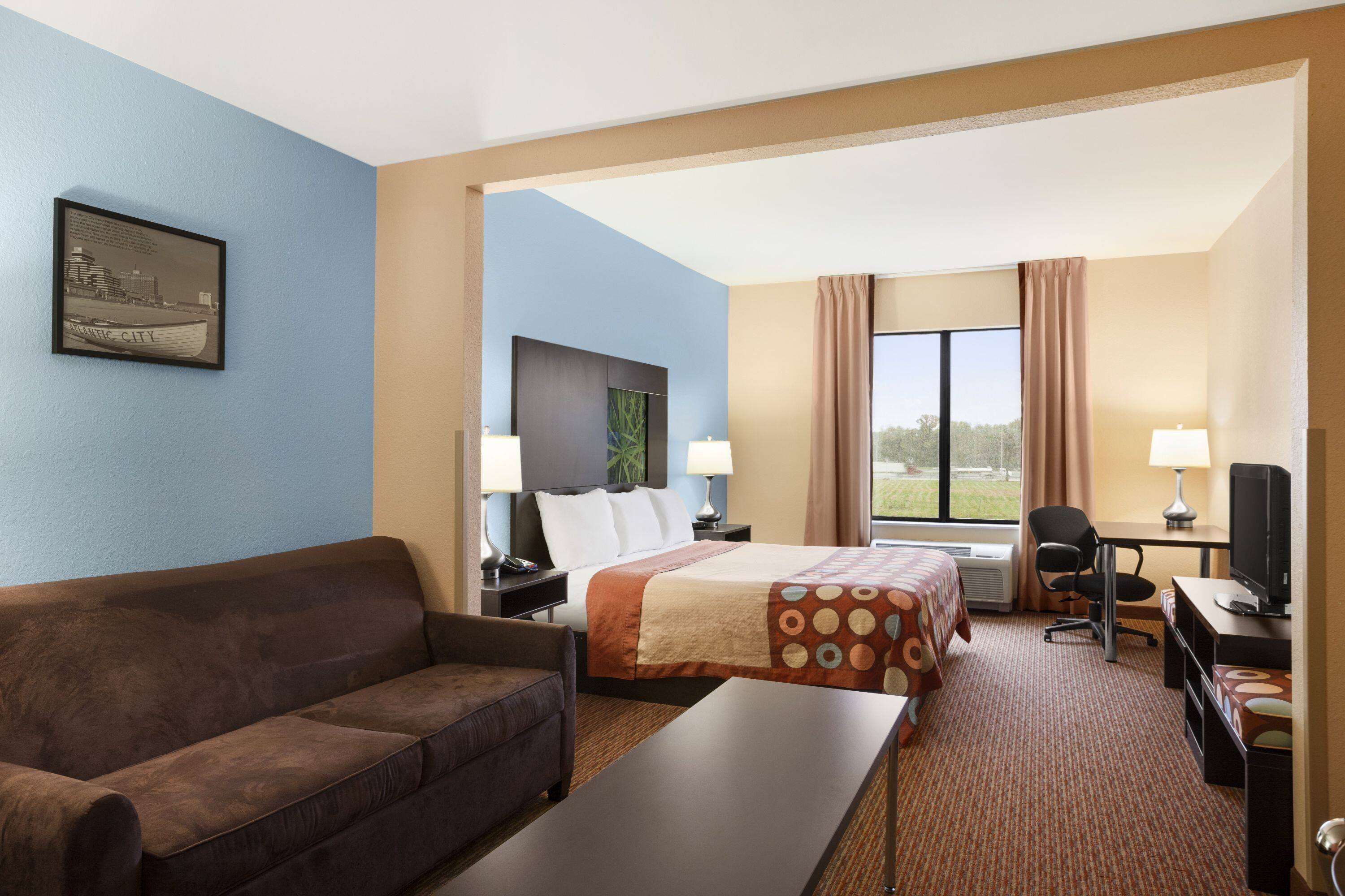 Ein Hotelzimmer mit einem Bett, einem Schreibtisch, einem Sessel, einer Couch und einem Fernseher.