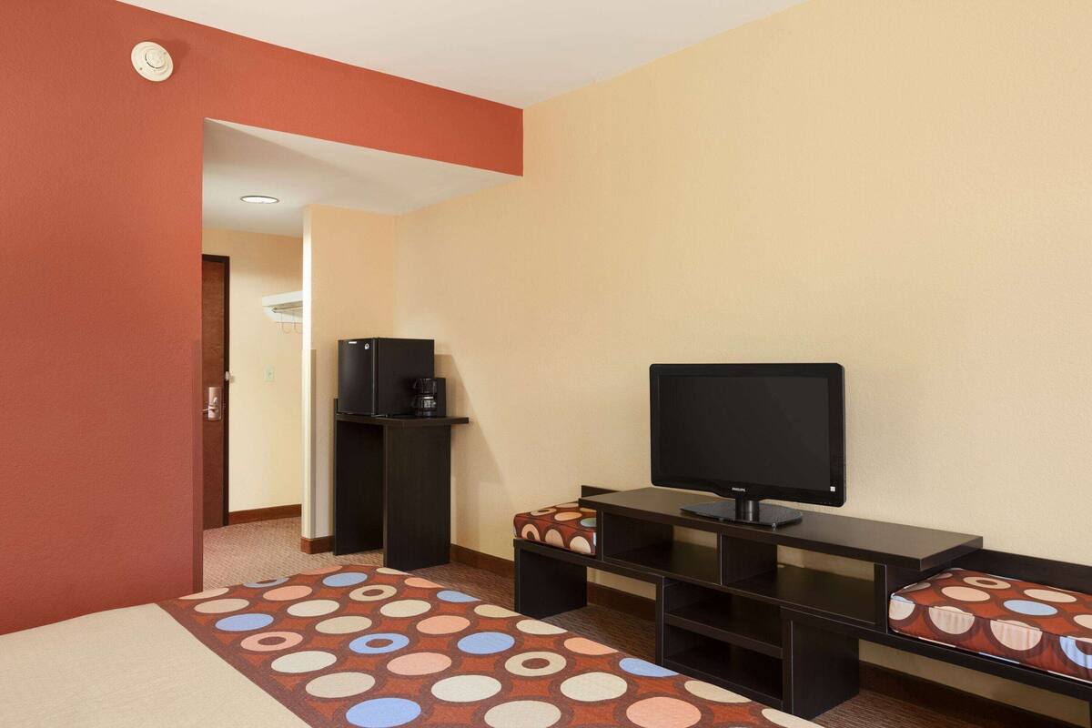 A hotel room with a bed, a desk, a television, and a coffee machine.