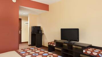 A hotel room with a bed, a desk, a television, and a coffee machine.