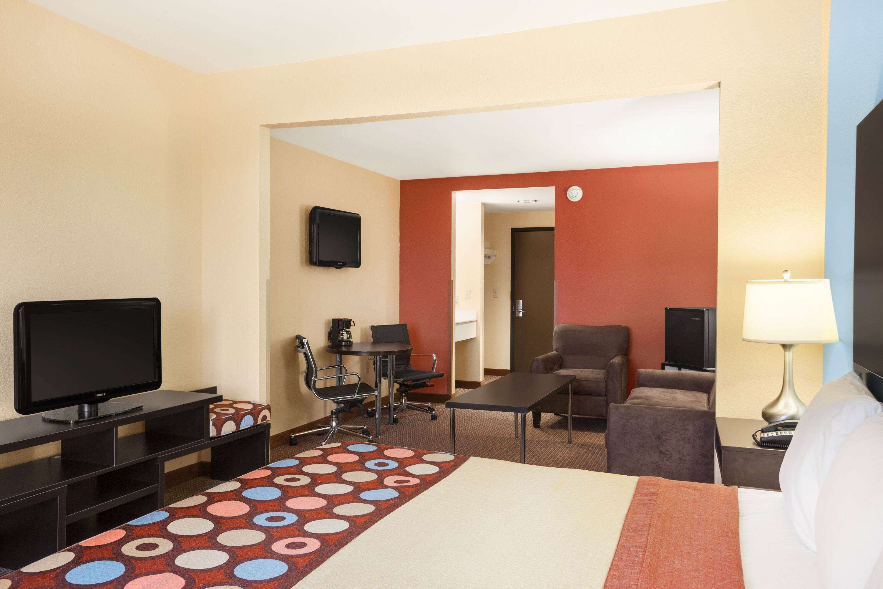 A hotel room with a bed, a desk with a computer, a television, a chair, and a sofa.