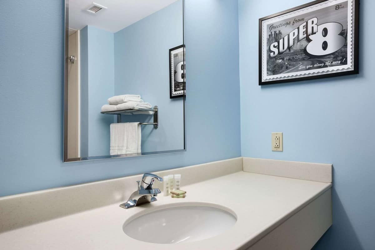 A bathroom with a sink, mirror, towel rack, and a framed picture on the wall.