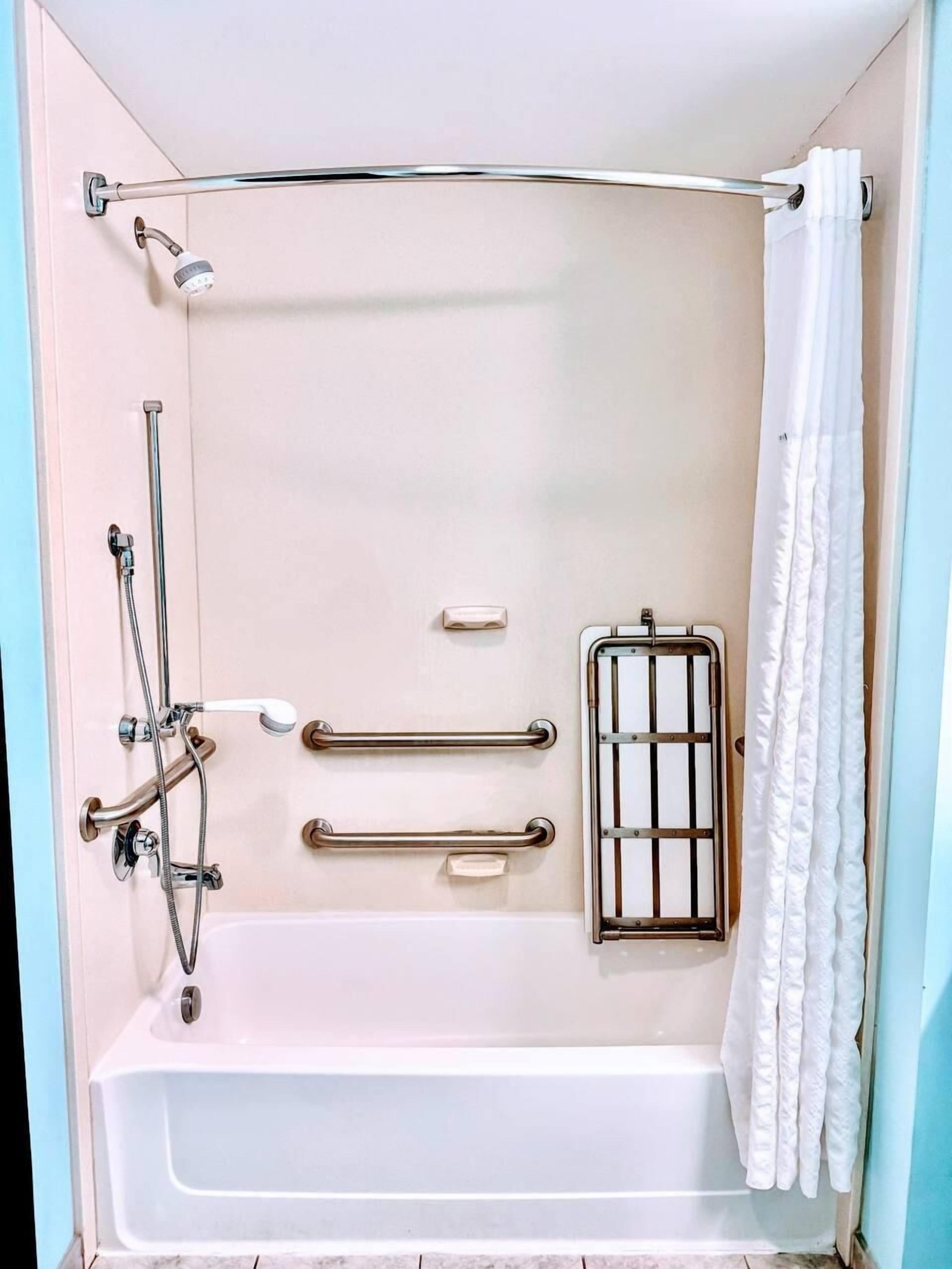 Un baño moderno con bañera, ducha y barras de apoyo.