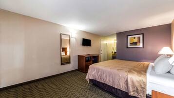 Una habitación de hotel con una cama, un tocador, un televisor y un cuadro en la pared.