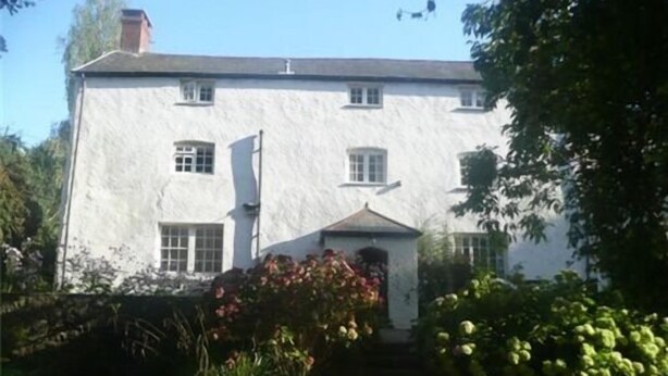 A two-story white building with a symmetrical facade, a central entrance with a triangular pediment, and a small porch area. - Church Farm Guest House (Monmouth)