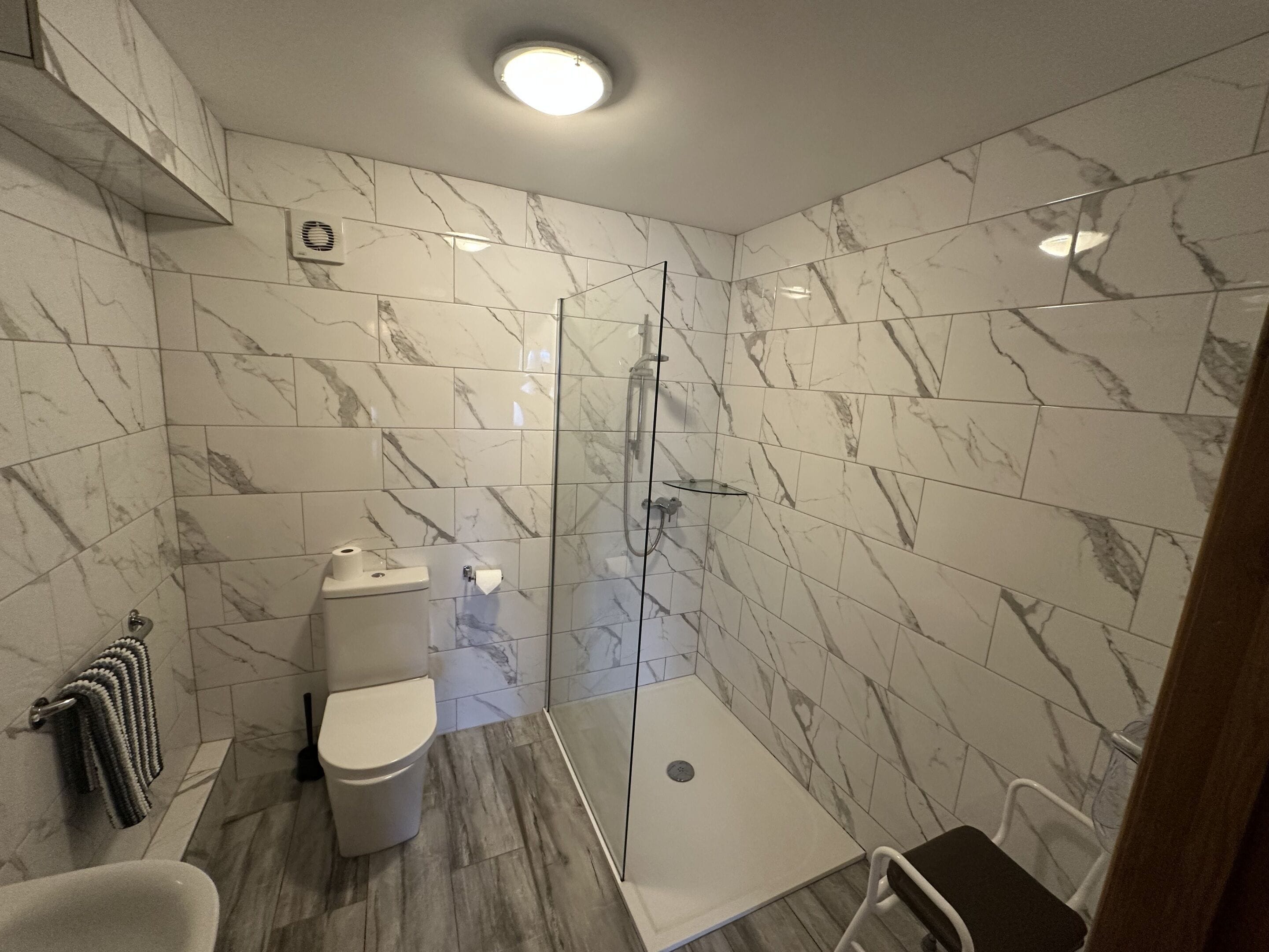 A modern bathroom with a glass-enclosed shower, a toilet, and a sink.