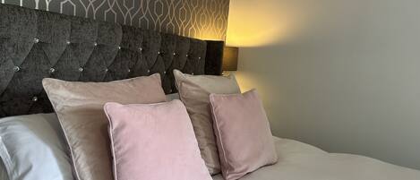 A bed with a tufted headboard, two pillows, and a patterned wall.