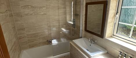 Ein Badezimmer mit einer Badewanne, einem Waschbecken, einer Toilette und einem Fenster.