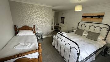 A bedroom with two single beds, a desk, and a mirror.