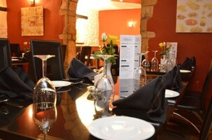 Un restaurante con mesas listas para comer, menús y un jarrón con flores.