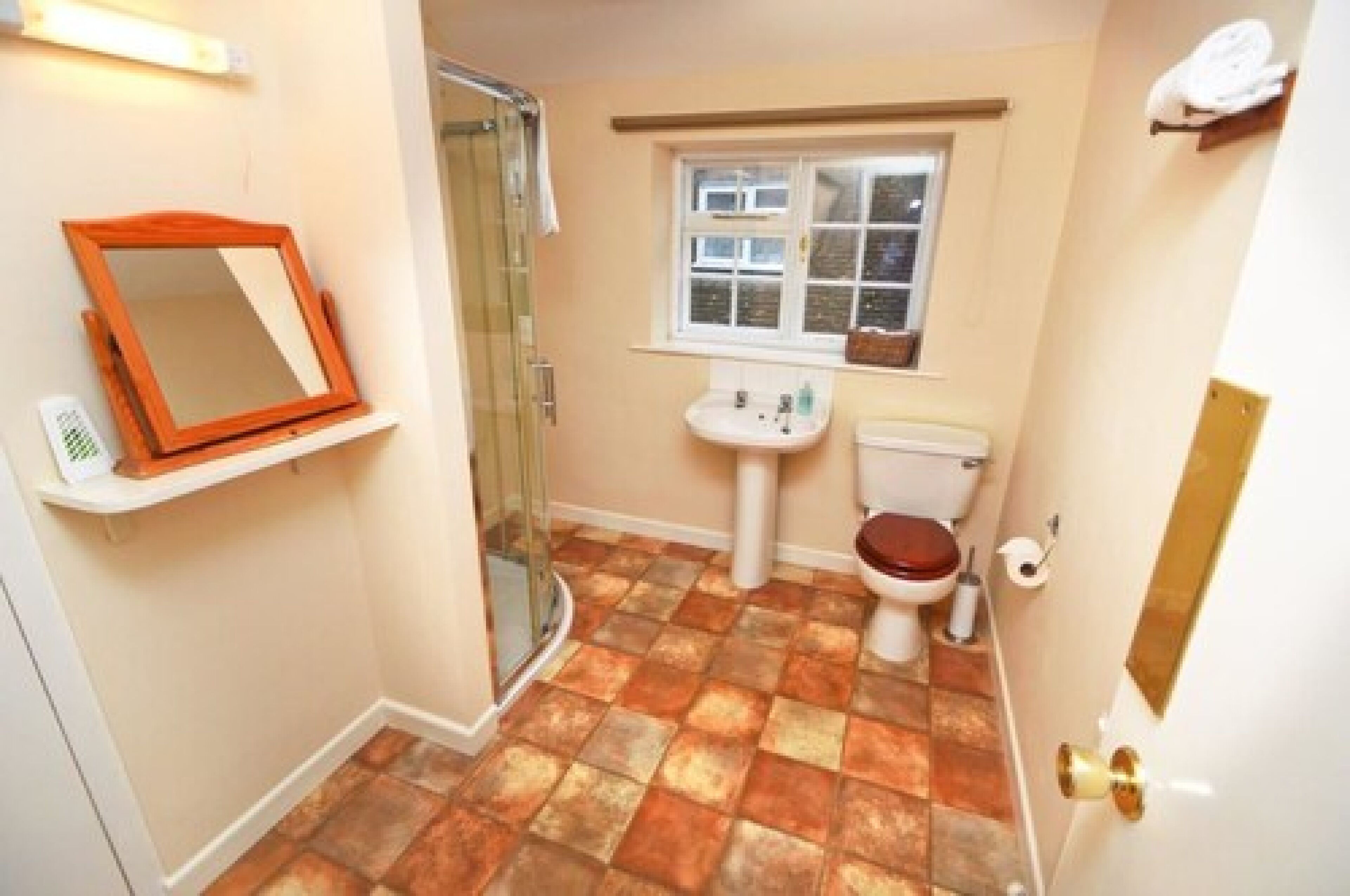 A bathroom with a shower, toilet, sink, and a window.