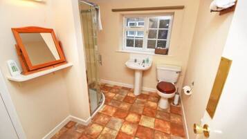 A bathroom with a shower, toilet, sink, and a window.
