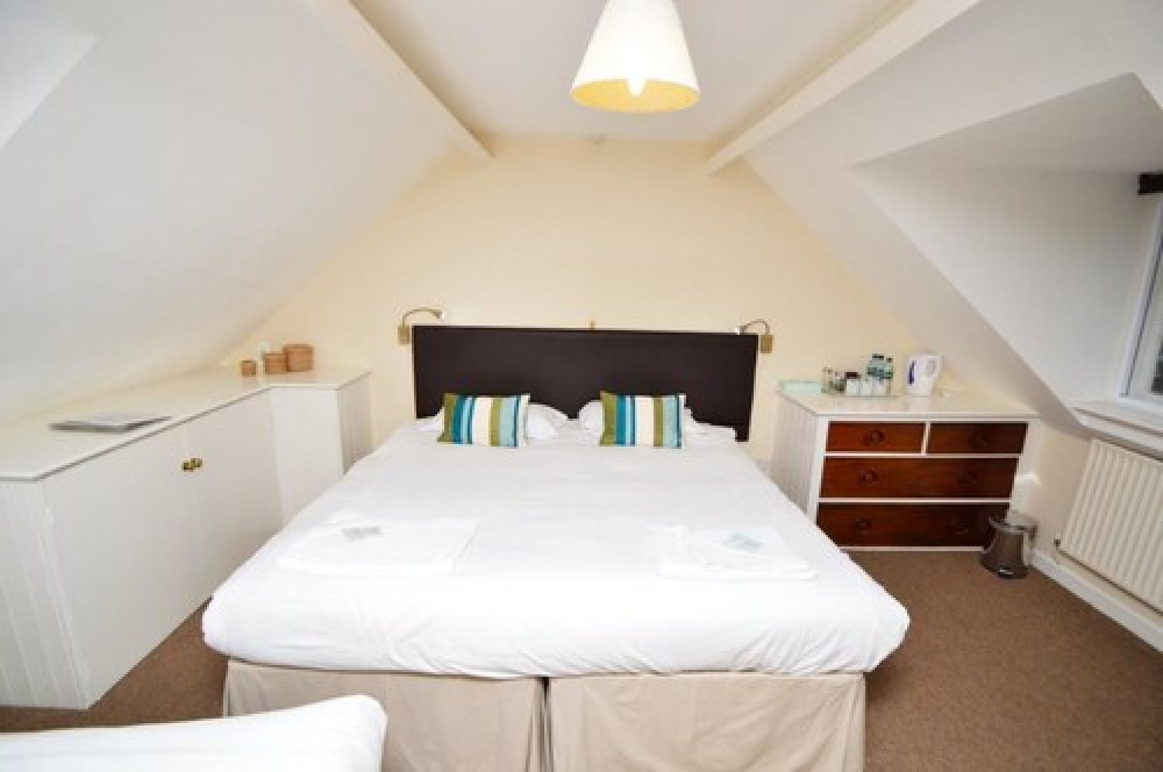 A bedroom with a bed, bedside tables, a dresser, and a radiator.