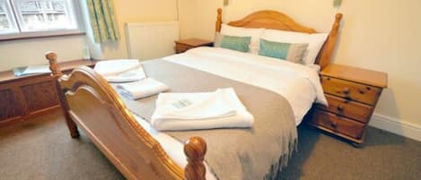 A neatly made bed with a wooden headboard, a bedside table, and a nightstand.