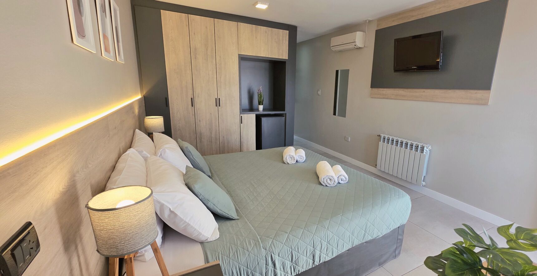 Quarto moderno com cama, luminária de cabeceira e armário embutido.