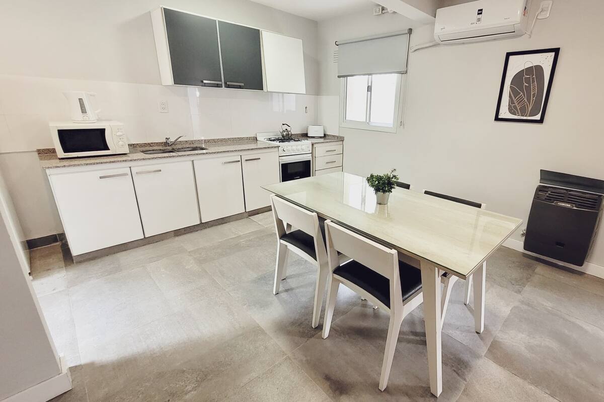 A modern kitchen with white cabinets, a dining table, and a black refrigerator.