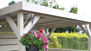 A covered outdoor seating area with a bench and a hanging flower pot. - Greenmount Bed & Breakfast (Belfast)