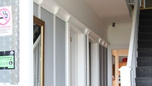 A hallway with a tiled floor, white walls, and a staircase with a white railing. - Greenmount Bed & Breakfast (Belfast)