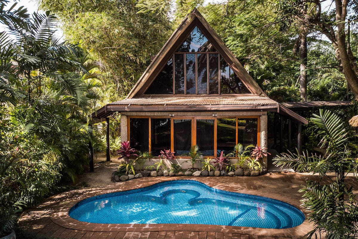 A house with a swimming pool surrounded by lush greenery.