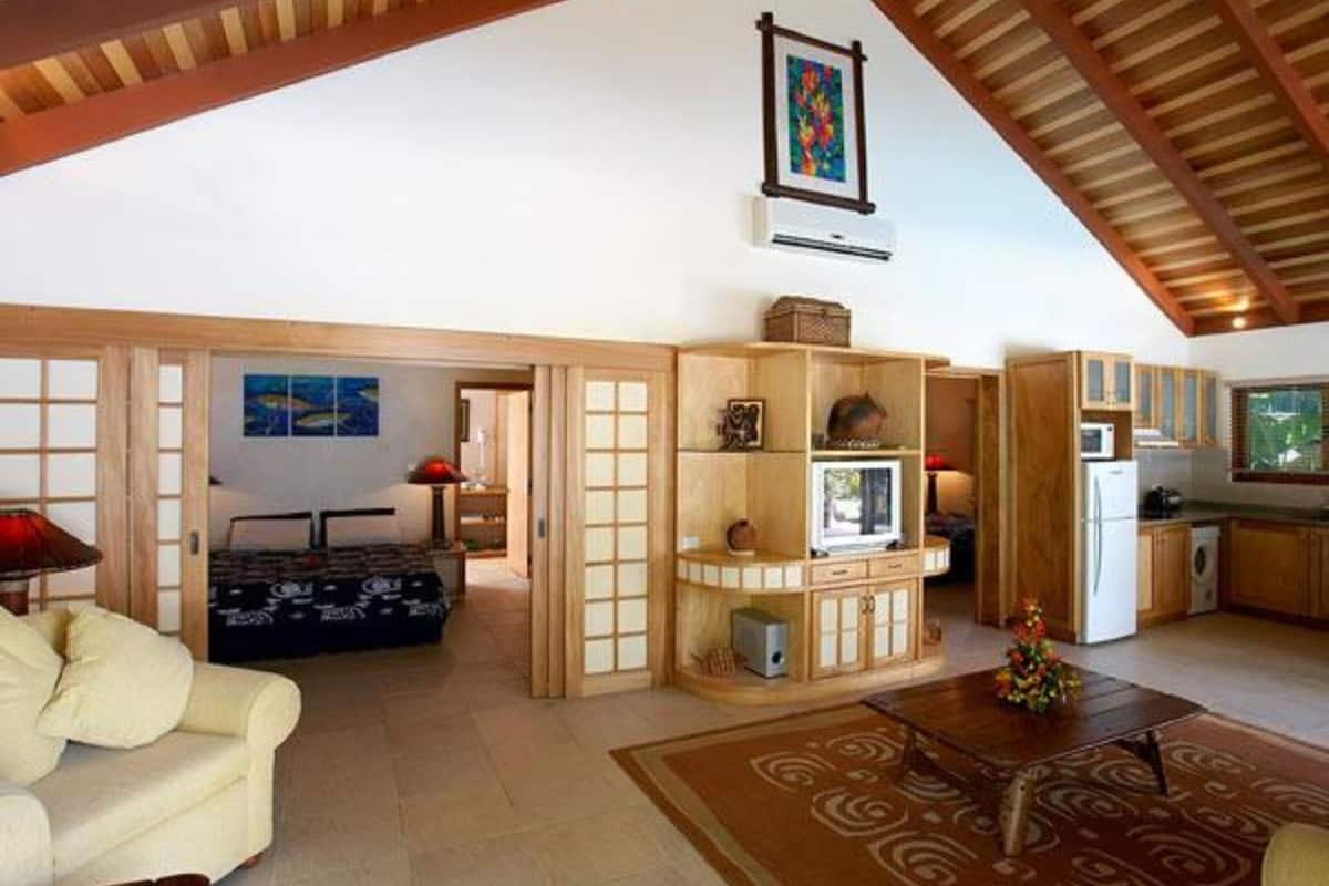 A spacious living area with a high ceiling, a sofa, a coffee table, and a kitchen area with cabinets and appliances.
