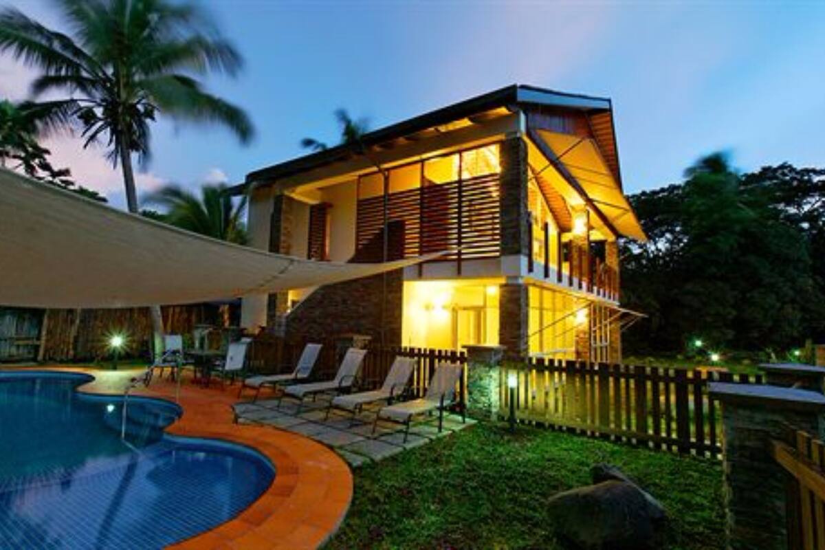 A modern two-story house with a swimming pool, outdoor seating, and a fenced yard.