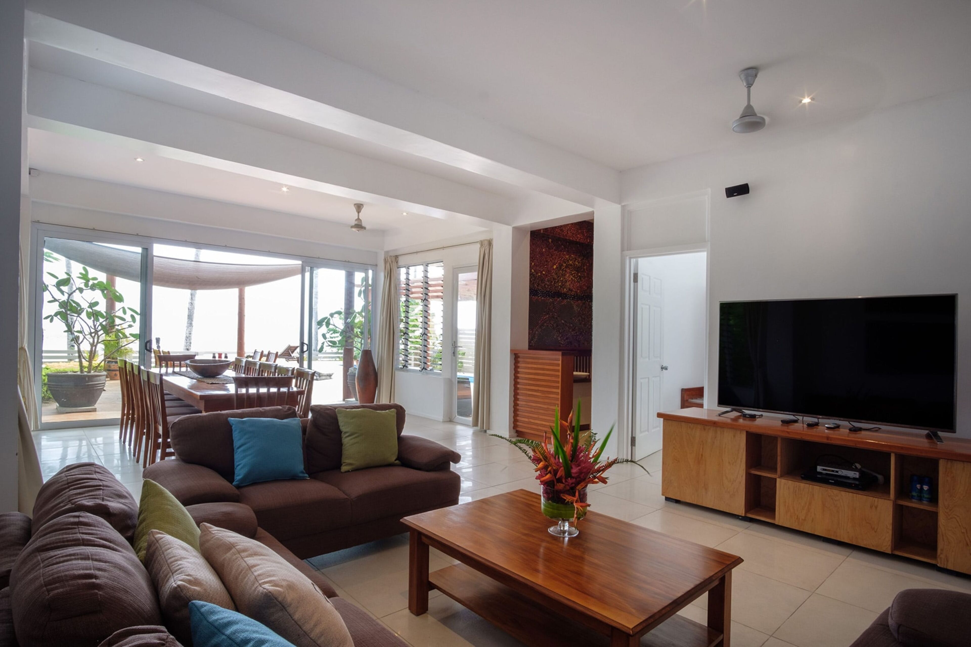 A modern living room with a large flat-screen TV, a wooden coffee table, and a sofa with cushions.