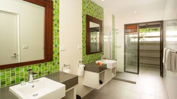 A modern bathroom with two sinks, a large mirror, and a glass shower enclosure.