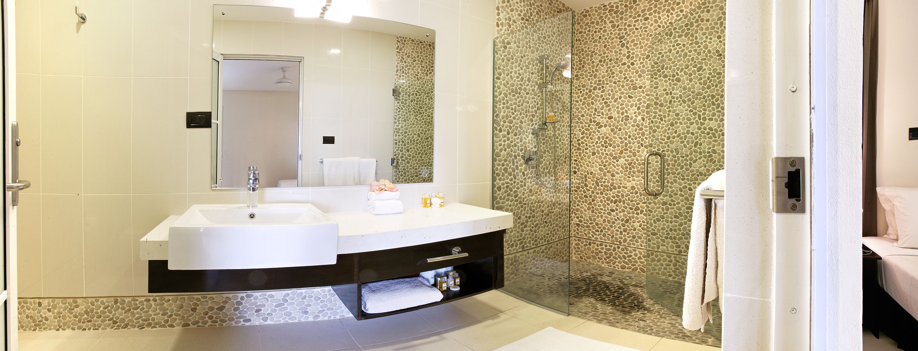 A modern bathroom with a double sink vanity, a glass-enclosed shower, and a large mirror.