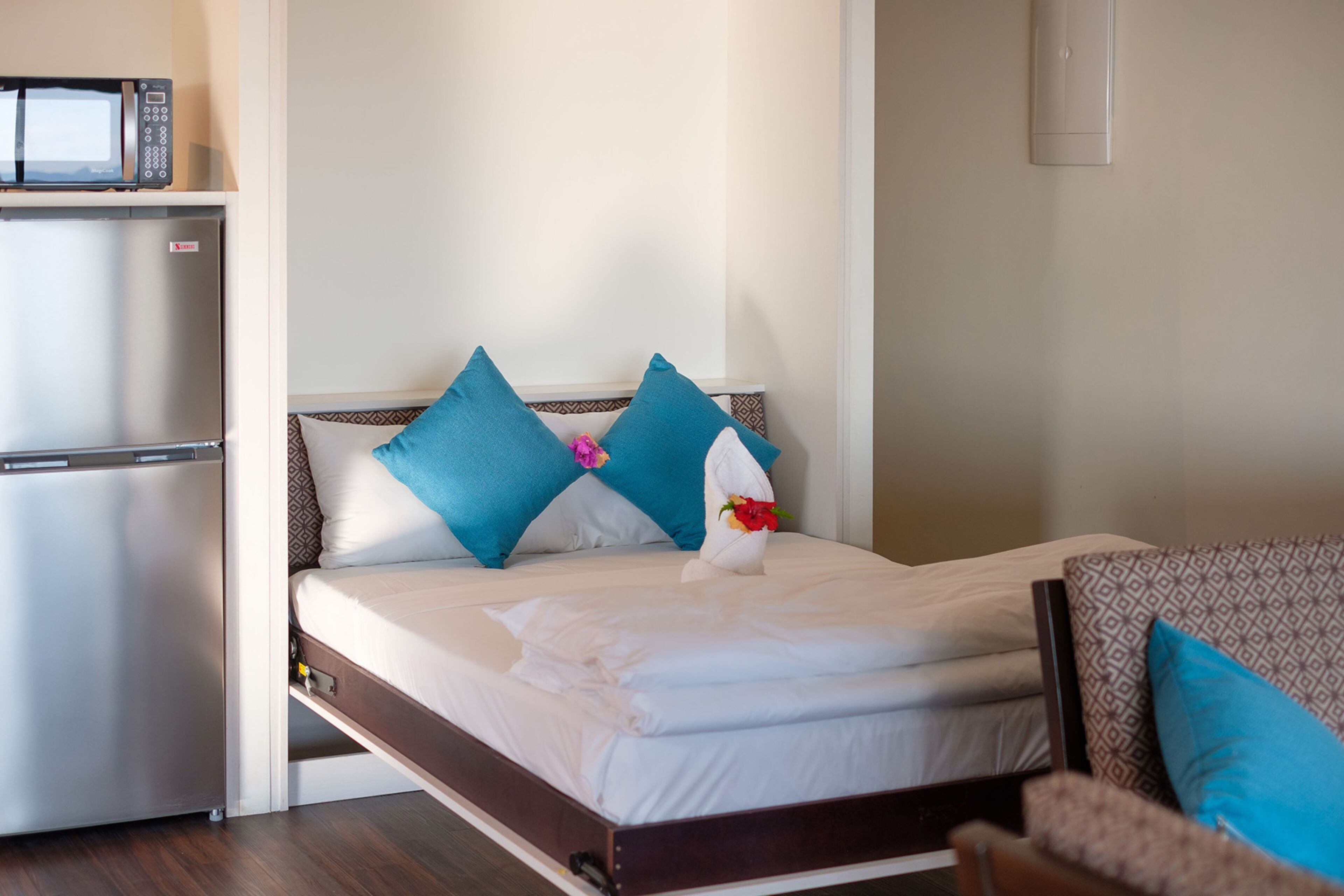 A hotel room with a bed, a microwave, and a refrigerator.