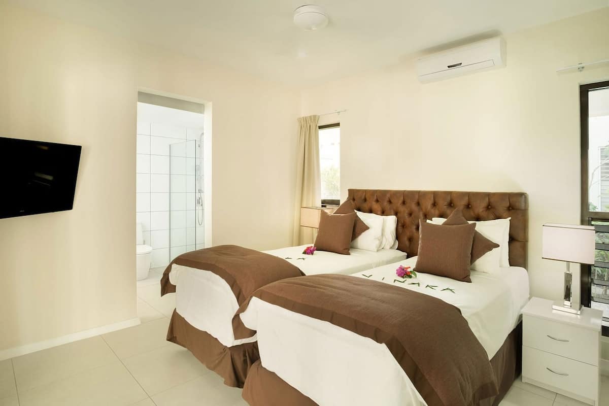 A hotel room with a large bed, a TV mounted on the wall, and a window with curtains.