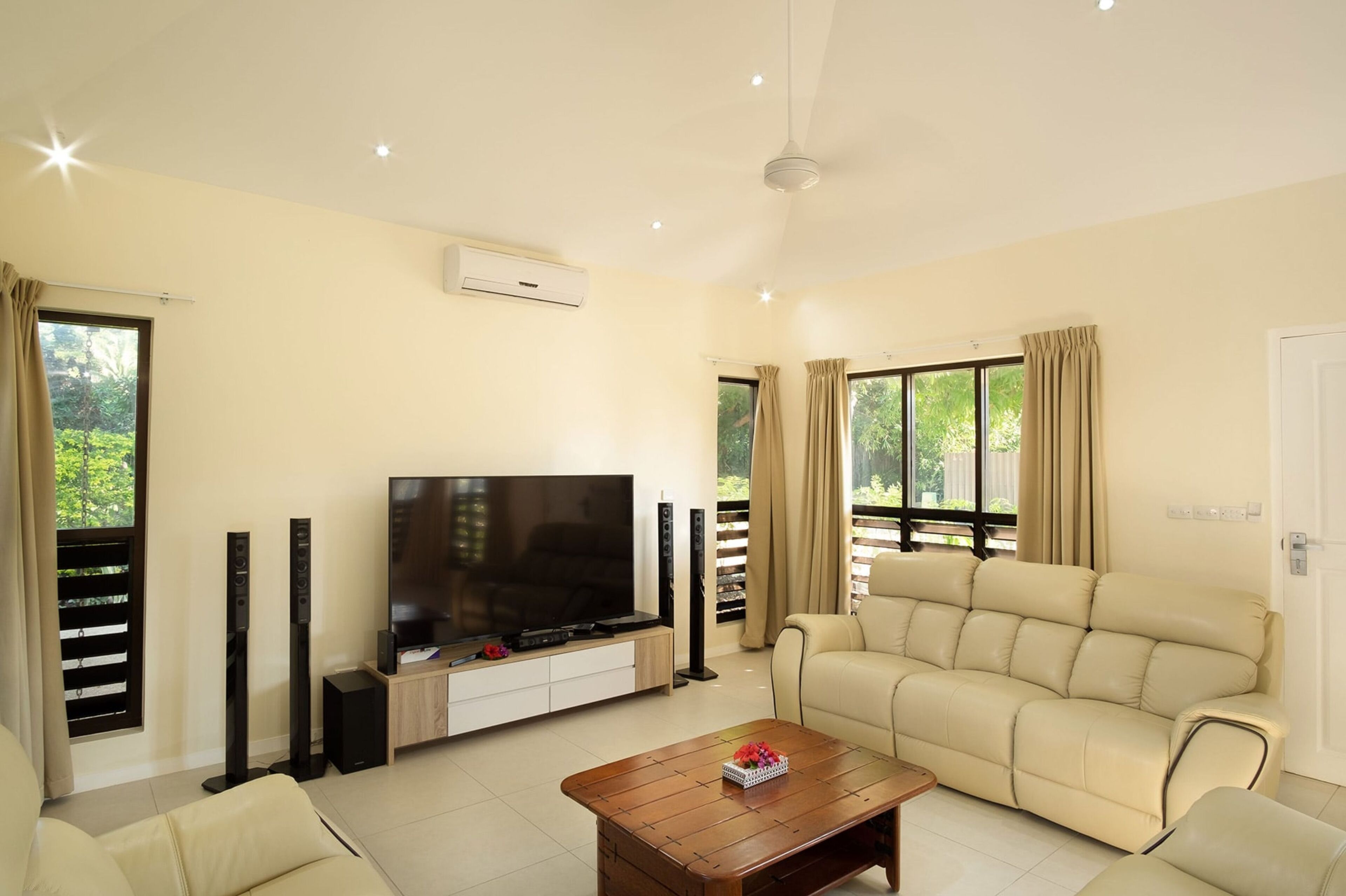 A living room with a flat-screen TV, beige sofa, and a coffee table.