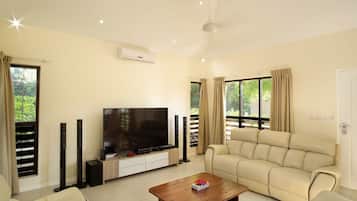 A living room with a flat-screen TV, beige sofa, and a coffee table.