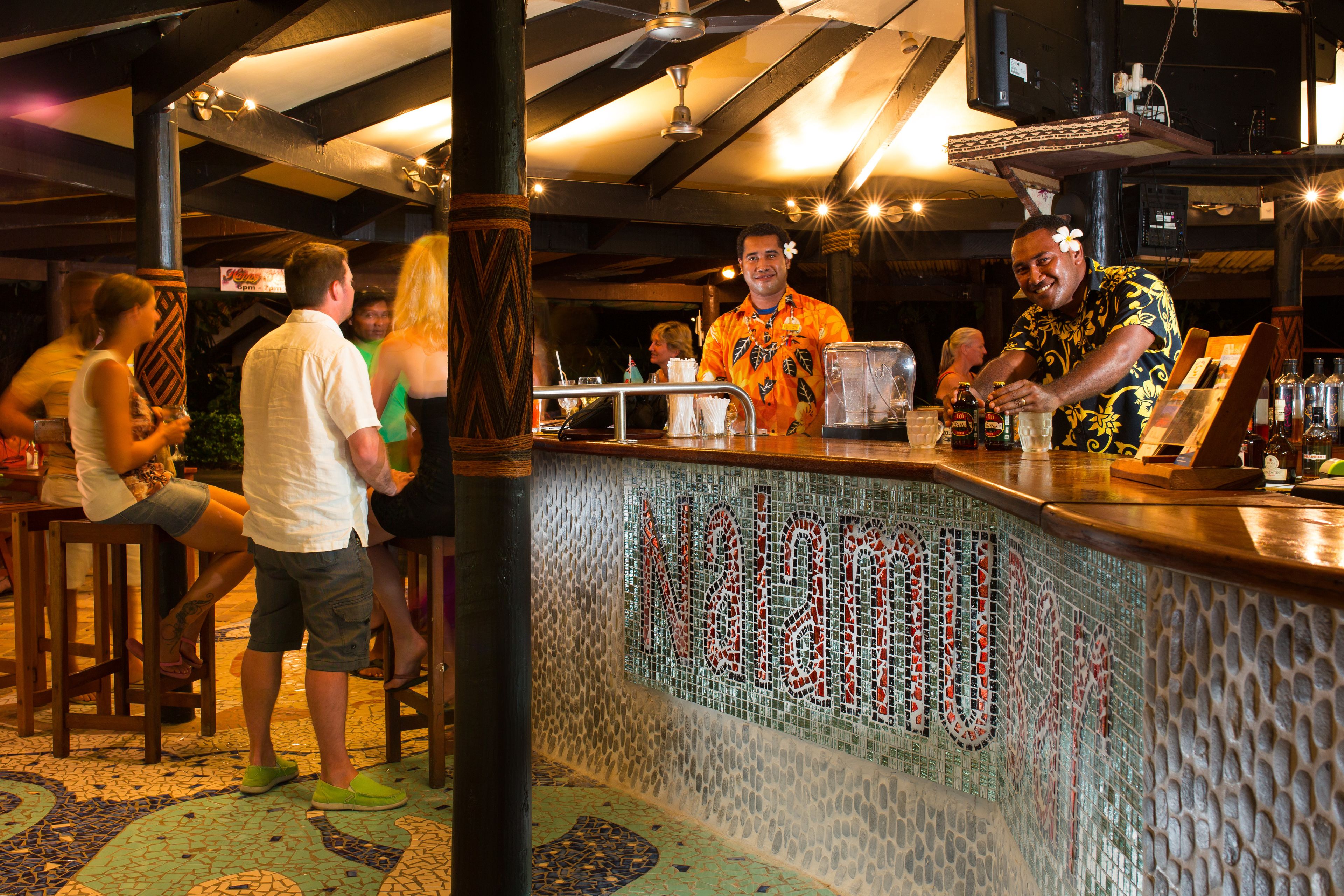 Un espace bar avec un comptoir, des tabourets et un mur décoratif en mosaïque.
