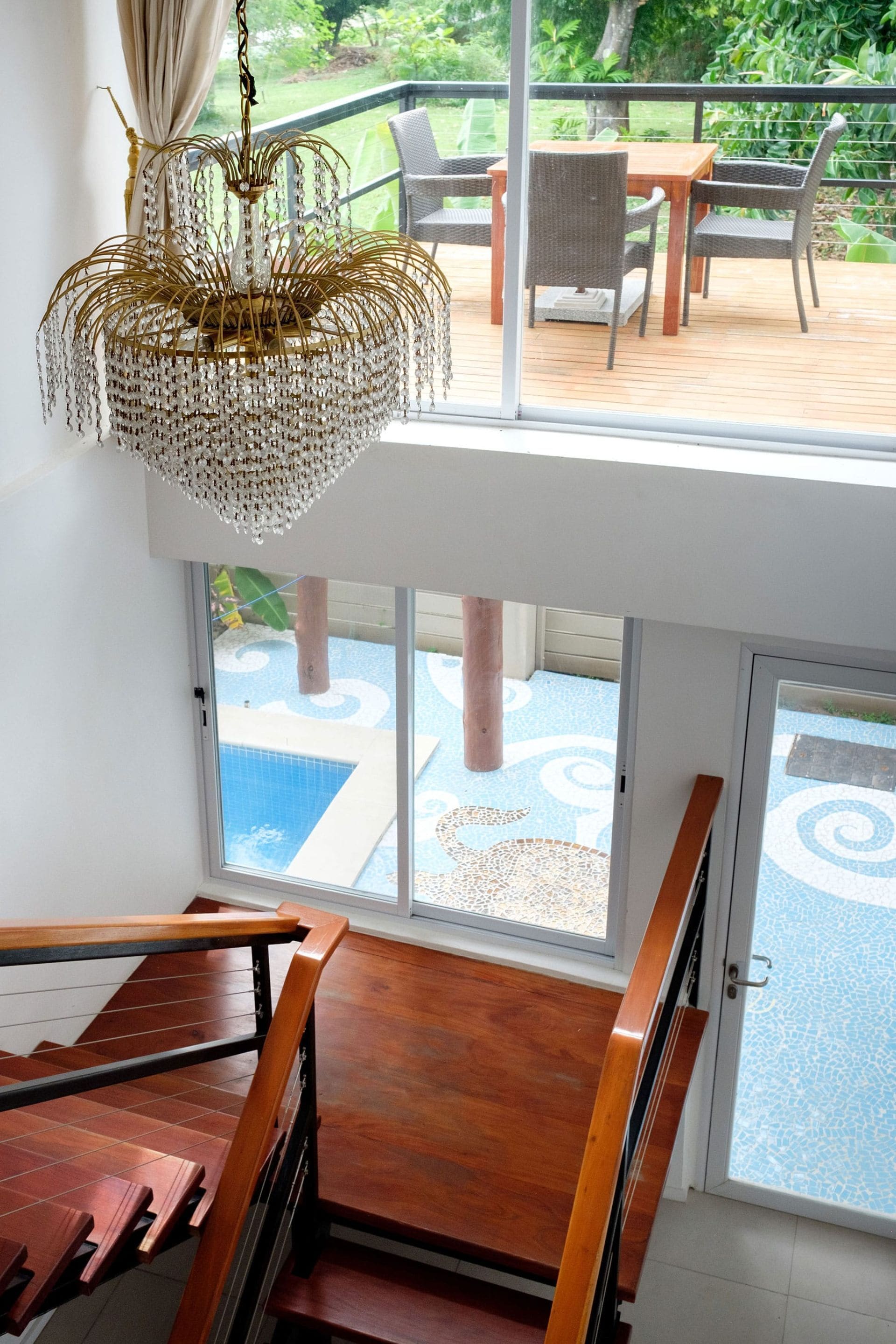 A wooden staircase leading to a balcony with a view of a pool and garden.