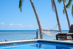 Una piscina al aire libre, sombrillas, sillones reclinables de piscina