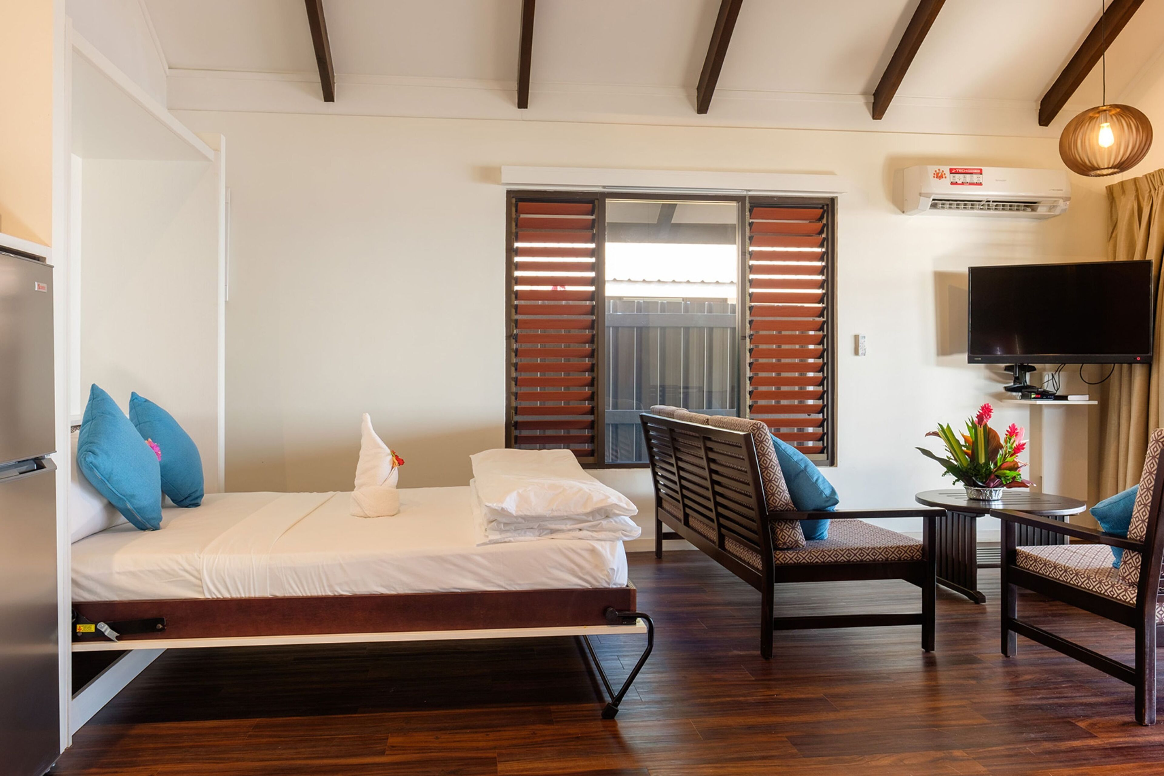 A hotel room with a bed, a TV, a chair, and a table.