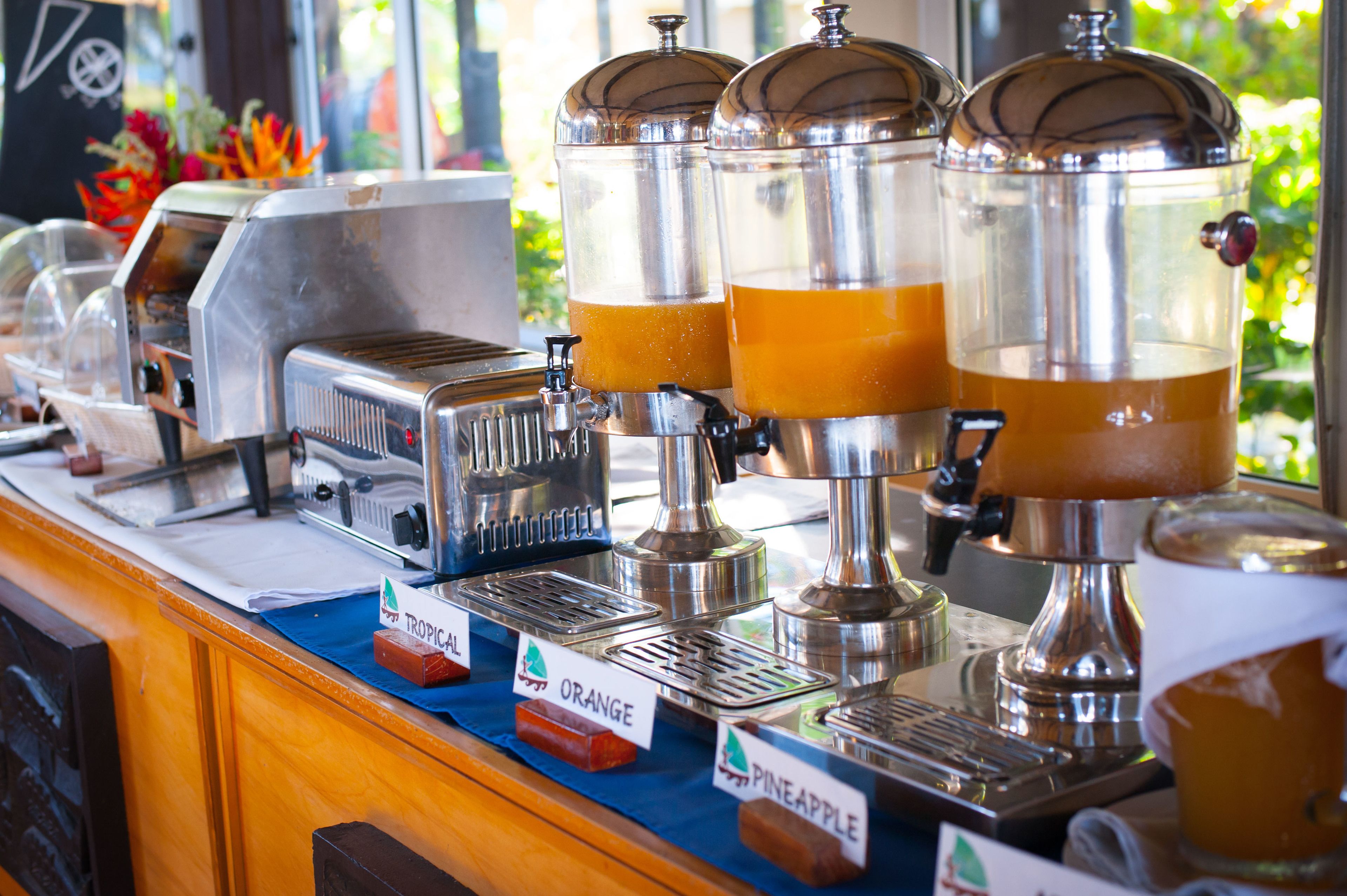 Una estación de café con varios dispensadores etiquetados 'TROPICAL', 'NARANJA' y 'PIÑA'.
