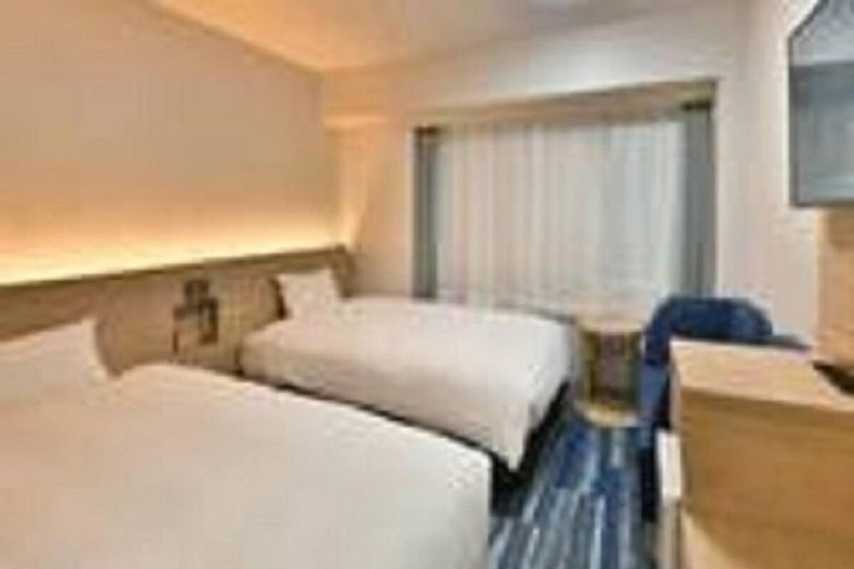 A hotel room with two beds, a desk, and a chair.