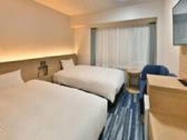 Habitación de hotel con dos camas, un escritorio y una silla.