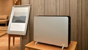 A modern room with a wooden panel wall, a framed informational sign, and a sleek, minimalist electronic device on a wooden table. - Nagoya Sakae Washington Hotel Plaza (Nagoya)