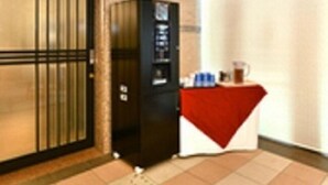A room with a closed door, a vending machine, and a small table with a red cloth. - Nagoya Sakae Washington Hotel Plaza (Nagoya)