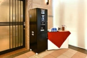 Una stanza con una porta chiusa, una macchina per snack e un tavolino con una tovaglia rossa.