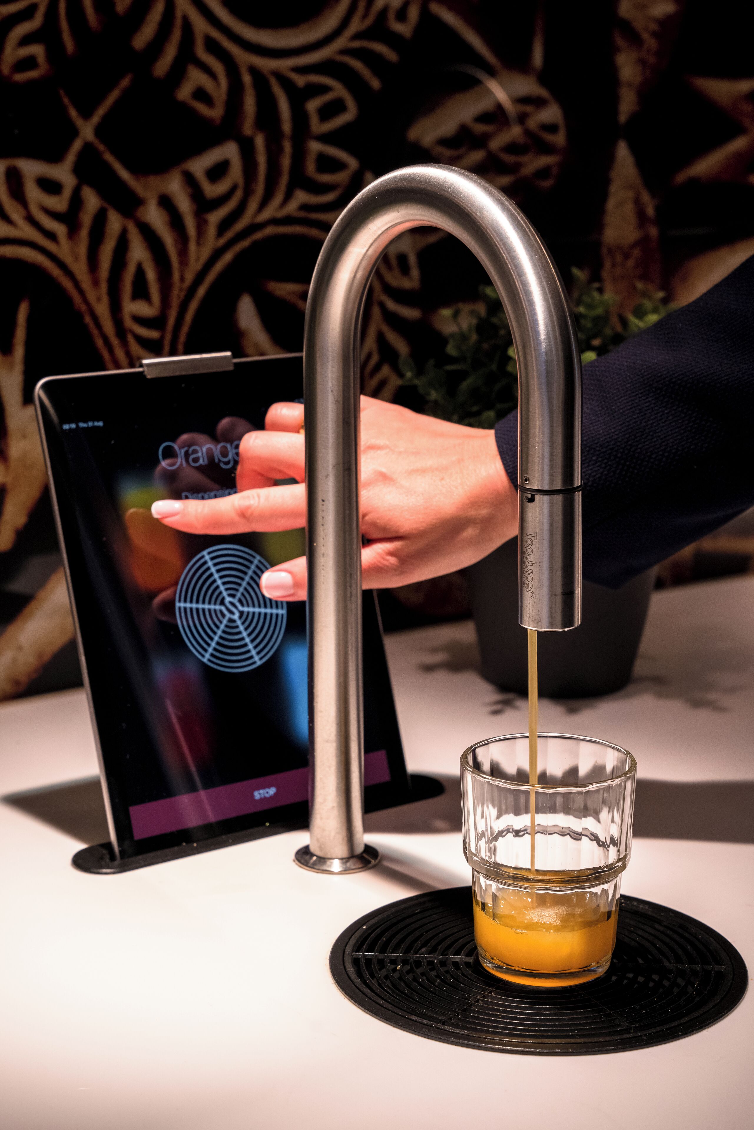 Una mano opera un grifo moderno para servir una bebida en un vaso.