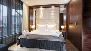 A modern hotel room with a large bed, a bedside table with a lamp, and a view through a window with sheer curtains. - Tallink Hotel Riga  (Riga)