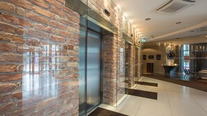 A modern lobby with a brick wall, a glass elevator, and a reception area. - Tallink Hotel Riga  (Riga)