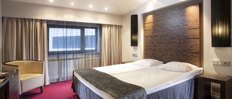 Una habitación de hotel moderna con una cama grande, un escritorio y una silla.