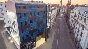 Een modern hotel met een blauwe gevel, gelegen aan een stadstraat met historische gebouwen.