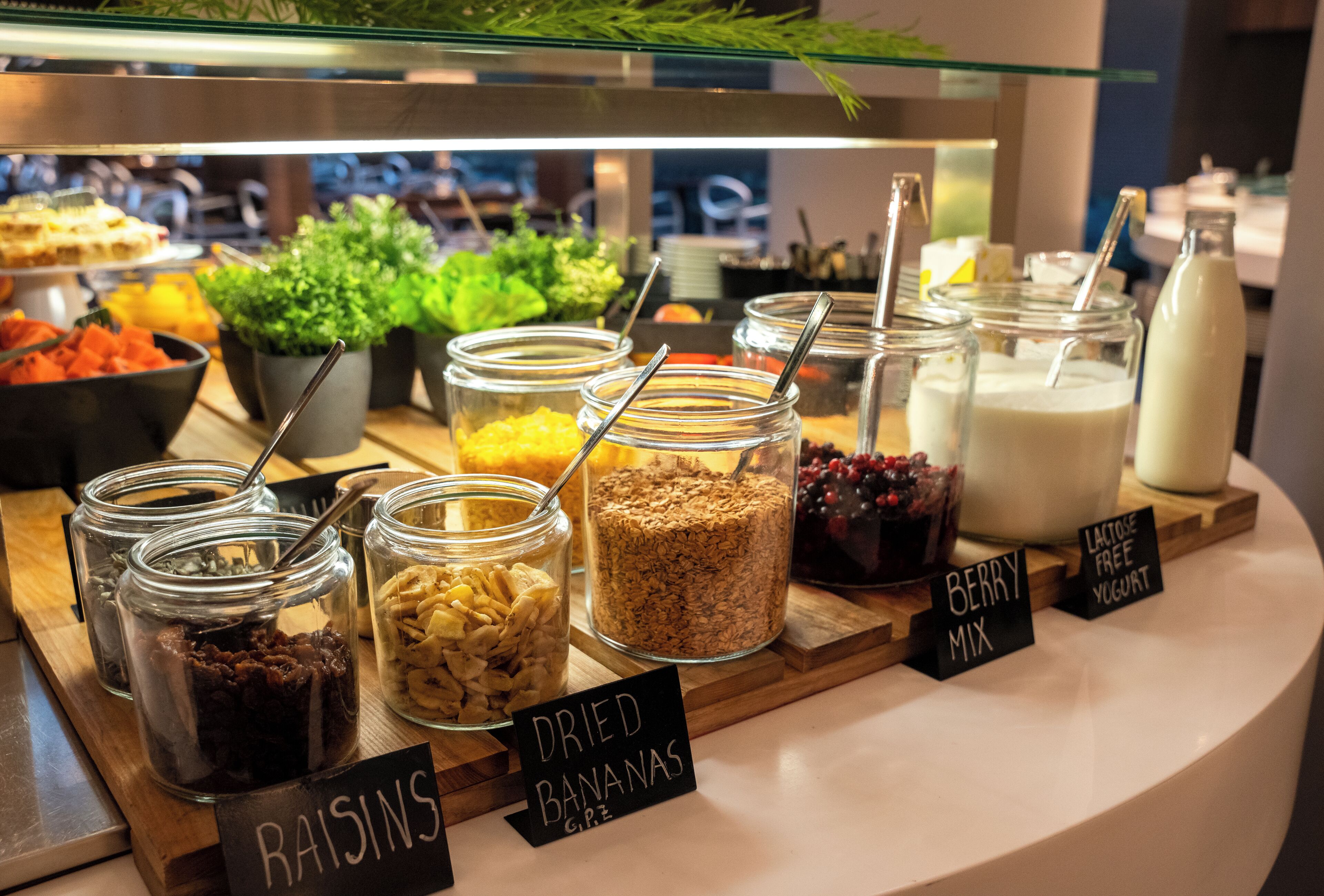 Un bufé con diversas opciones de comida, incluyendo plátanos deshidratados, bayas y pasas.